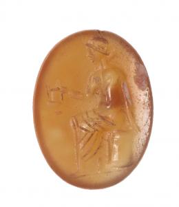 480  -  ROMA. Imperio Romano. Cornalina. II-III d.C. Entalle con respresentación maculina sentada sujetando un ánfora. Longitud 15 mm.