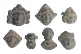 ROMA. Imperio Romano. II-IV d.C. Bronce. Lote de 7 objetos: 5 apliques con representación de Atis, un busto masculino y una máscara de esclavo. Altura 16-22 mm.