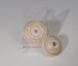 PRÓXIMO ORIENTE. Mesopotamia. Par de fusayolas (3000-2000 a.C.). Alabastro. Con perforación central. Diámetro 3,1 y 3,9 cm.