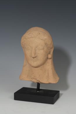 GRECIA. Cabeza de Koré (VI-IV a.C.). Terracota. Altura 15,2 cm. Incluye peana.