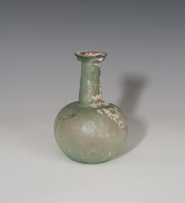 ROMA. Imperio Romano. Botella (Segunda mitad II d.C.). Depósito esférico achatado, cuello largo y boca moldurada. Presenta irisaciones y exfoliaciones. Altura 15,3 cm.