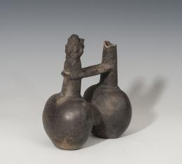 PREHISPÁNICO. Cultura Chimú. Botella de doble cuerpo (1100-1470 d.C.). Cerámica de barniz negro. Con silbato antropomorfo. Altura 16,6 cm. Extremo roto.