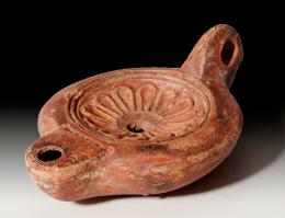 ARQUEOLOGÍA. ROMA. Imperio Romano. Lucerna (finales I-principios II d.C.). Cerámica. Pasta anaranjada, piquera circular, un agujero de llenado y disco central decorado con roseta. Marca "L DOMITI R". Longitud 10,6 cm.