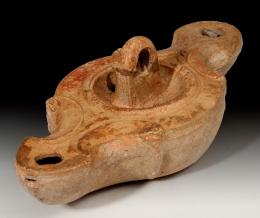 ARQUEOLOGÍA. ROMA. Imperio Romano. Lucerna (II-III d.C.). Cerámica. Pasta anaranjada, dos piqueras circulares en cada extremo, dos agujeros de llenado y disco central del que parte una arandela. Longitud 16,5 cm.