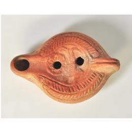 PERIODO PALEOCRISTIANO. Lucerna con piquera circular, dos agujeros de llenado y disco central decorado con un cánido en su parte central, alrededor motivos geométricos. Norte de África, siglos IV-V d. C. Terracota. Longitud 12,5 cm.