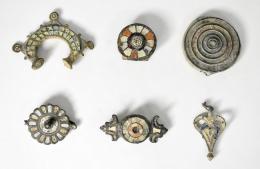 ROMA. Bajo Imperio. Lote de 6 bronces tardorromanos: tres apliques, dos fíbulas y un colgante, con decoraciones en pasta vítrea (s. V d.C.). Bronce con esmalte. Longitud de 3,3 a 7 cm.