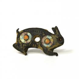ROMA. Imperio Romano. Botón / aplique en forma de conejo decorado con dos círculos con pasta vítrea de color rojo, naranja y turquesa (ss. III-IV d.C.). Bronce . Ojo pegado. Longitud 28 mm. 