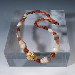 2008 - ARQUEOLOGÍA. PERSIA. Imperio Aqueménida. Collar de cuentas con cuenta central representando un león alado. Siglo IV a.C. Ágata, cornalina y pasta vítrea recubierta de lámina de oro. Cierre moderno. Longitud 64 cm.
