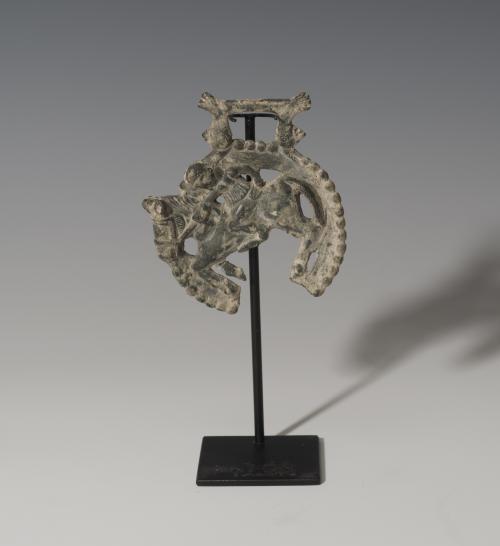 853   -  ROMA. Imperio Romano. Cama de freno izquierdo de caballo (III-IV d.C.). Bronce. Con representación de jinete a izquierda. Altura 9,2 cm. Diámetro 7,6 cm. Roto