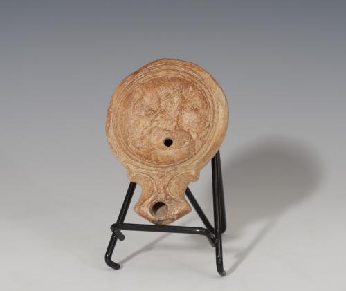 462 - ROMA. Imperio Romano. Lucerna (I d.C.). Terracota. Piquera angular de punta con voluta, un agujero de llenado y disco central decorado con felino a derecha. En la base inscripción incisa. Longitud 10,4 cm.