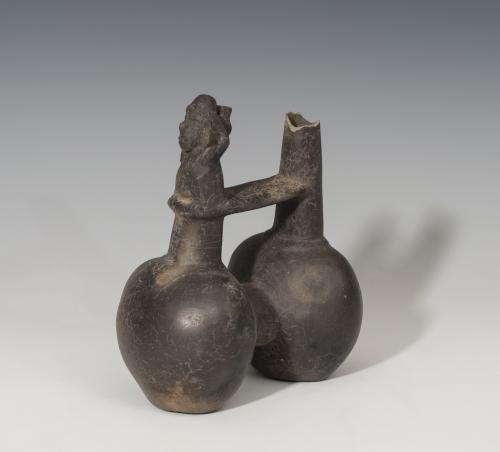 493   -  PREHISPÁNICO. Cultura Chimú. Botella de doble cuerpo (1100-1470 d.C.). Cerámica de barniz negro. Con silbato antropomorfo. Altura 16,6 cm. Extremo roto.