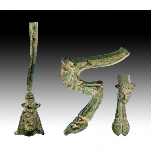2712 - ROMA. Imperio Romano. Lote de dos objetos (II-IV d.C.). Bronce. Pie / soporte de trípode con representación de cabeza de Sátiro y asa de jarro con representación de cabeza masculina. Altura: 8,6 y 13,2 cm.