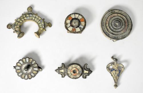 2071 - ROMA. Bajo Imperio. Lote de 6 bronces tardorromanos: tres apliques, dos fíbulas y un colgante, con decoraciones en pasta vítrea (s. V d.C.). Bronce con esmalte. Longitud de 3,3 a 7 cm.