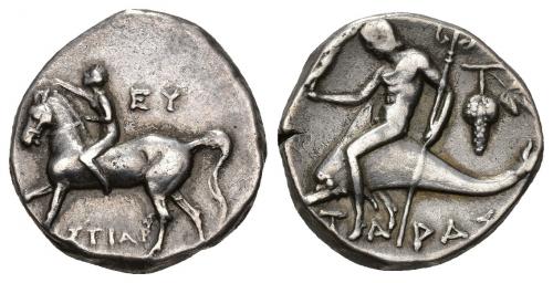 17 - GRECIA ANTIGUA. CALABRIA. TAREENTO. Didracma (c. 272-235 a.C.). A/ Jinete a izq. coronando su caballo; EU/H)ISTIAR. R/ Taras cabalgando delfín a izq con Niké y tridente, detrás racimo de uvas, debajo TAPAS. AR 6,31 g. 17,9 mm. COP-917. SBG-no. Pequeña grieta. MBC. Ex subasta Jesús Vico 1 (20-3-1986), lote 2.