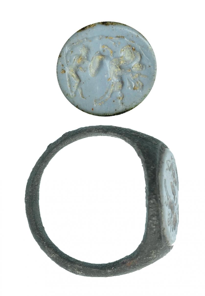 733   -  ROMA. Imperio Romano. Bronce y calcedonia azul. Anillo con entalle con representación de jinete con lanza a izquierda atravesando a un guerrero caído a derecha. Detrás árbol. Diámetro: 15 mm. Procedente de colección privada española años 1970-80.