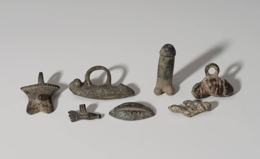 852   -  ROMA. Imperio Romano. Lote de siete  objetos (I-II d.C.). Bronce. Cinco amuletos fálicos, una mano y una vulva. Altura 3,2-4,4 cm. Longitud 2,1-4,3 cm.