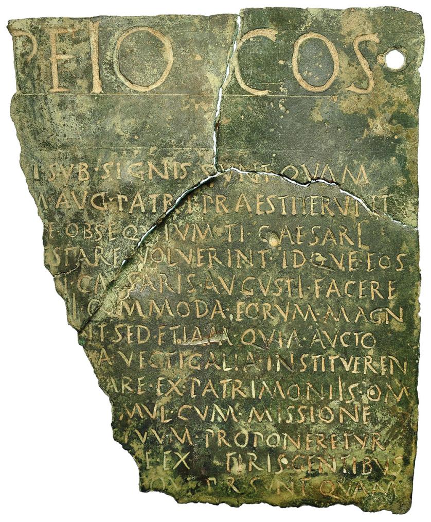 2009   -  ARQUEOLOGÍA. ROMA. Imperio Romano. Fragmento de placa epigráfica de bronce correspondiente al epígrafe jurídico romano con inscripción en latín. El frag­mento a su vez se encuentra partido en tres partes contiguas, dos superiores y una inferior. Las dimensiones son de 18,7 cm de altura máxima, 15,1 cm de ancho por la parte superior y 10,2 cm por la parte inferior. En la parte superior de la placa se conserva un taladro de 7mm de diámetro para fijación de la inscripción a una pared. El texto, en letras mayúscu­las, grabadas por percusión, se compone de una primera linea claramente diferenciada de las siguientes trece lineas, por ser su módulo de un tamaño muy superior. Además, esta primera linea también se diferencia del resto en que esta separa­ da del cuerpo del texto por una franja sin grabar delimitada por dos final lineas incisas horizontales. La transcripción de la placa es la siguiente: (...)PEIO · COS . / (...)VI· SVB · SIGNIS ·SVNT · QVAM/ (...) M · AVG ·PATRI · PRAES TITERVNT/ (...) VE · OBSEQVIVM · TI · CAESARI/ (...) ESTARE ·VOLVERI NT · IDQVE · EOS (...)/ TI · CAESARIS · AVGVSTI · FACERE /(...) + I · COMM ODA · EORVM · MAGN/ (...) NT · SED · ETIAM ·QVIA · AVCTO/(...) +A· VECTIGALIA · INSTITVEREN/ (...) +ARE · EX · PATRIMONIIS · OM/ (...) IMVL · CVM · MISSIONE/ (...) TITVVM · PROPONERETVR/ (...) SE · EX(uacat)TIRIS · GENTIBVS/ (...) EQVE · P R · SVNT · QVAM. Adjunta análisis XRF realizado por el laboratorio SGS Tecnos. Referencias bibliográficas sobre esta pieza:A. Caballos Rufino, 
