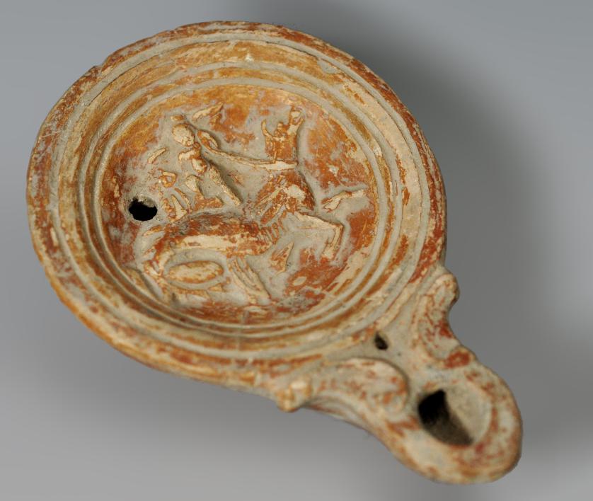 2026   -  ARQUEOLOGÍA. ROMA. Imperio Romano. Lucerna (ss. II-III d.C.) Piquera circular, un agujero de llenado y disco central decorado con un amorcillo que tira de un hipocampo. Terracota. Longitud 11,8 cm.