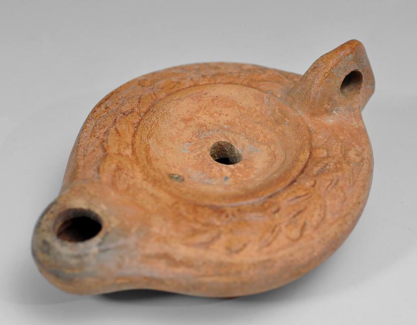 2027   -  ARQUEOLOGÍA. ROMA. Imperio Romano. Lucerna (ss. siglo I-III d.C.), con decoración vegetal, piquera circular y un agujero de llenado. Terracota. Longitud 11,5 cm.