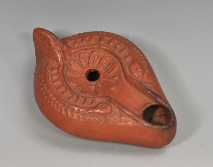 2050   -  ARQUEOLOGÍA. PERIODO PALEOCRISTIANO. Lucerna  con piquera circular, un agujero de llenado y disco central, decorado con motivos vegetales. Norte de África, siglos IV-V.  Terracota. Longitud 12,5 cm.	