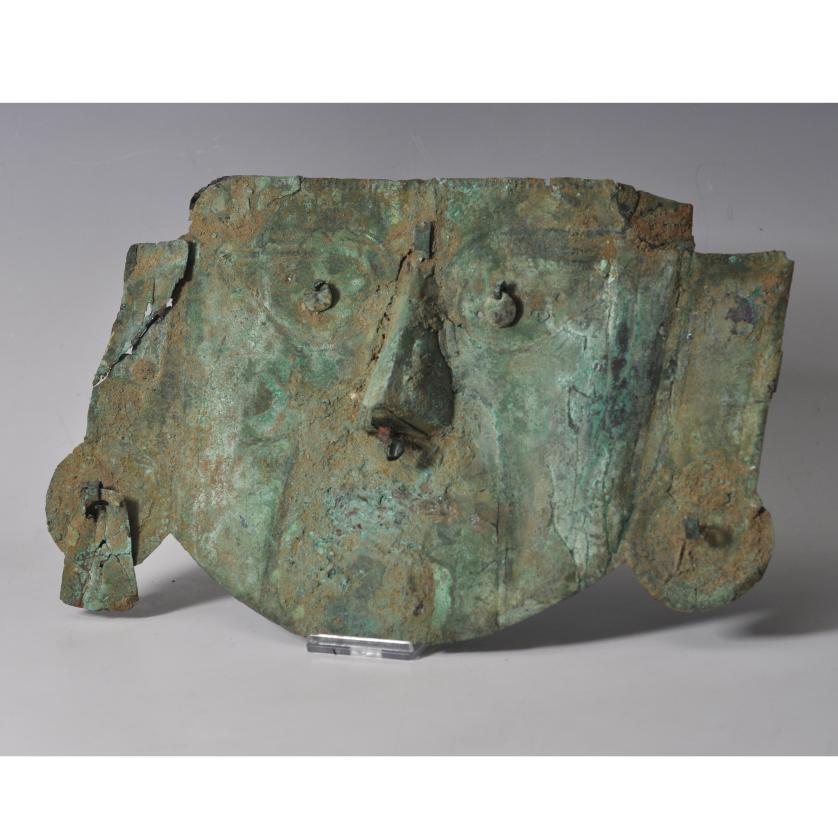 2051   -  PREHISPÁNICO. Fragmento de pectoral en forma de máscara, representando al dios Neylan. Cultura Sicán (700-1375 d.C). Cobre. Algunas pérdidas en los laterales. Longitud 25,5 cm.