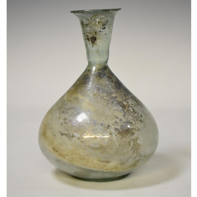 2060   -  ROMA. Imperio Romano. Botella globular (ss. II-IV d.C.), con cuello troncocónico y boca exvasada. Vidrio. Presenta irisaciones. Altura 17,5 cm. 