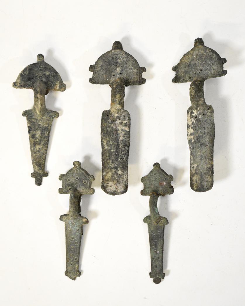 2080   -  PUEBLOS GERMÁNICOS. Período visigodo. Lote de 5 fíbulas con decoración geométrica en forma de pequeños círculos (ss. V-VII d.C.). Pátina verdosa. Bronce. Longitud entre 8,3 y 11,5 cm.