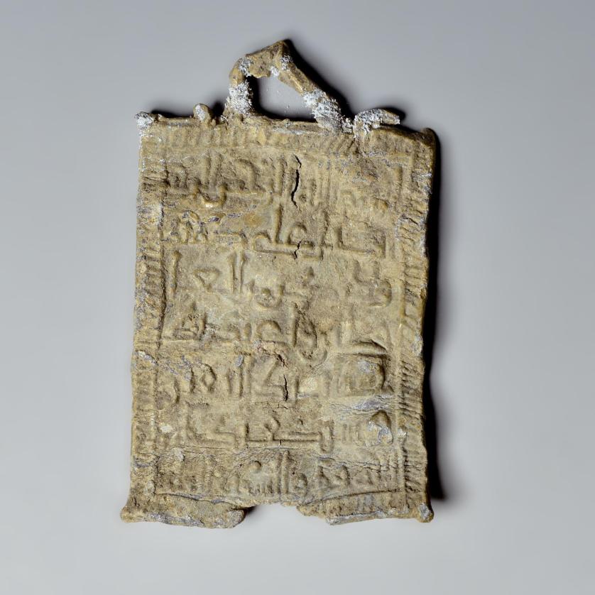 2028   -  ARQUEOLOGÍA. EDAD MEDIA. Hispano musulmán. Lámina con escritura árabe por ambas caras (ss. X-XII d.C.). Forma rectangular con una asita en la parte superior. Plomo. Algunas pérdidas y grietas. Longitud 5,5 cm x 3,2 cm.