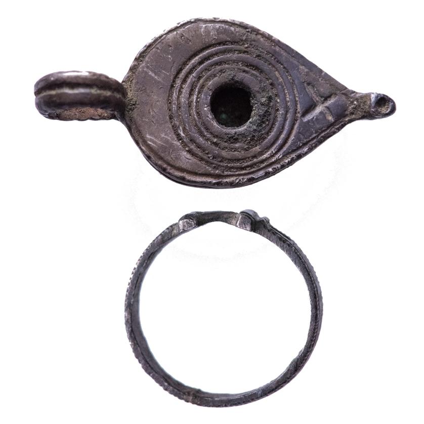 2054   -  ARQUEOLOGÍA. BIZANCIO. Lote de 2 objetos: un broche o colgante en forma de lucerna y un anillo.  Siglo V-VI d.C. Plata. Longitud de 1,9cm a 3,4 cm.