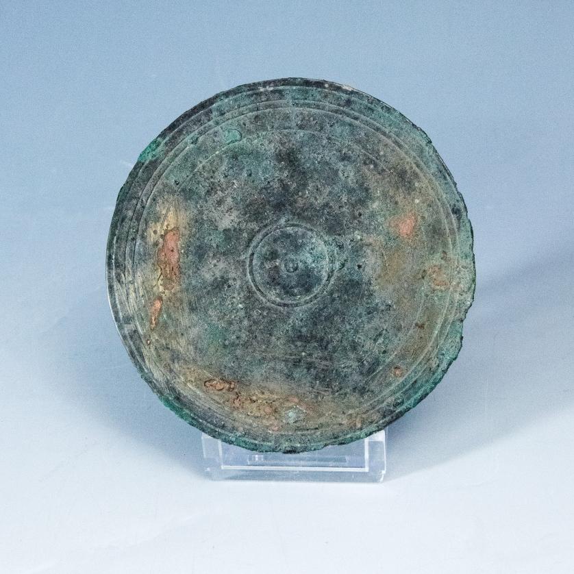 2035   -  ARQUEOLOGÍA. ROMA. Imperio Romano. Espejo con orla de círculos y fragmento de mango (ss. I-IV d.C.). Bronce. Diámetro 90cm, longitud del mango 6,6 cm.
