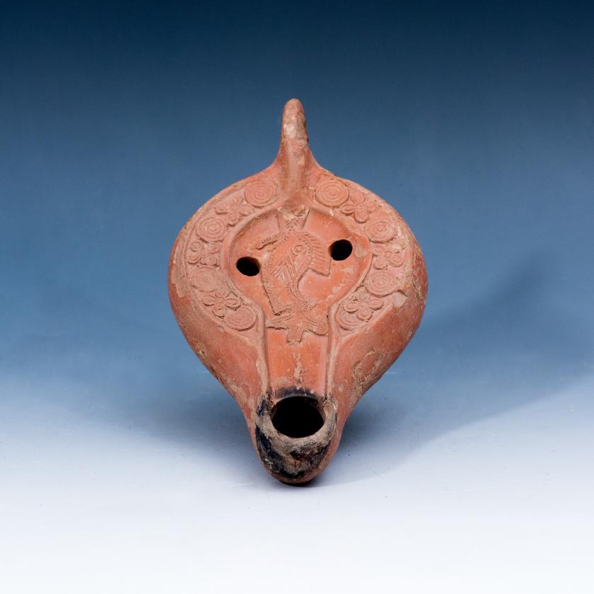 3031   -  ARQUEOLOGÍA. BIZANCIO. Lucerna con piquera circular, decorada con figura pisciforme en su centro, rodeada por decoración floral y geométrica (ss. V-VI d.C.). Terracota. Longitud 15 cm. Intacta.