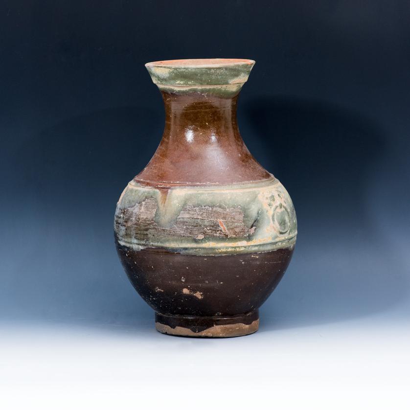 3033   -  ARQUEOLOGÍA. CHINA. Dinastía Han. Vasija destinada a grano, vidriada en marrón y franja central con máscaras de Taotie (206 a.C.-220 d.C.). Cerámica. Altura 30 cm.